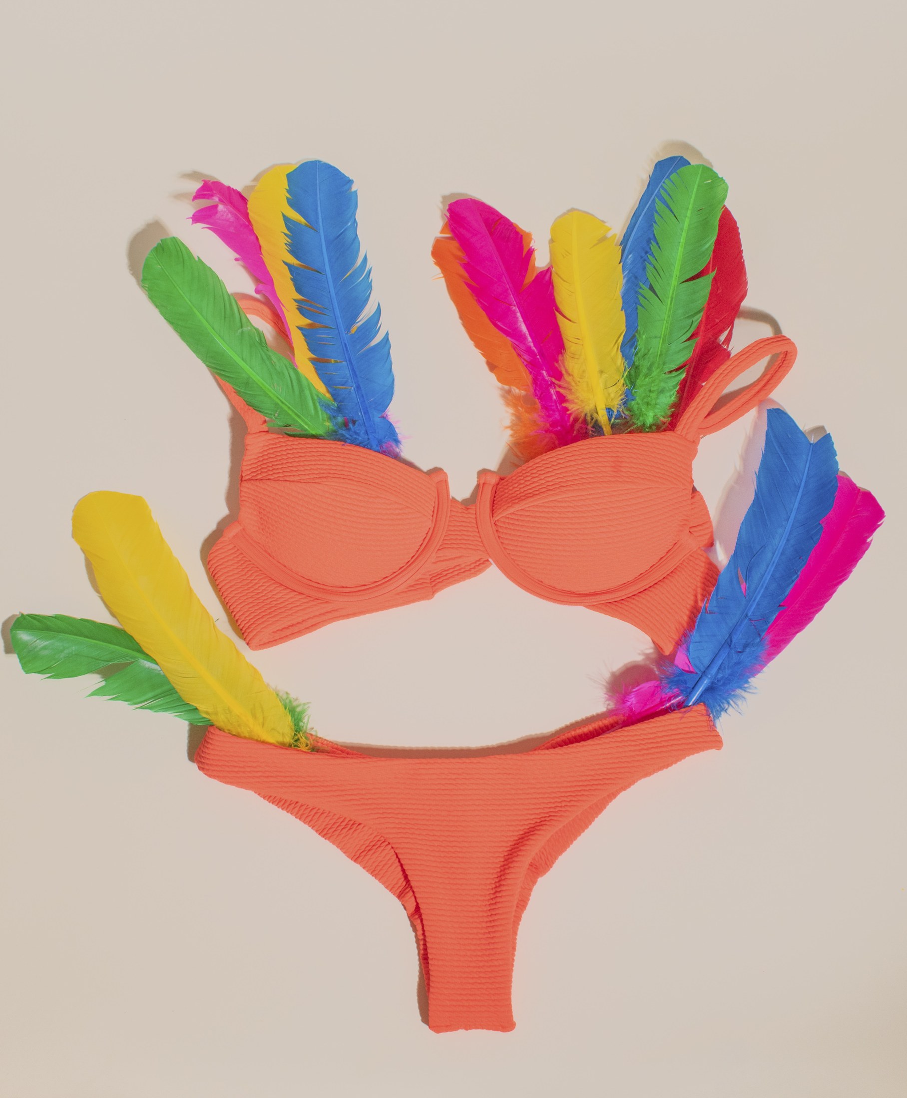 Orange swimwear styled with colorful feathers