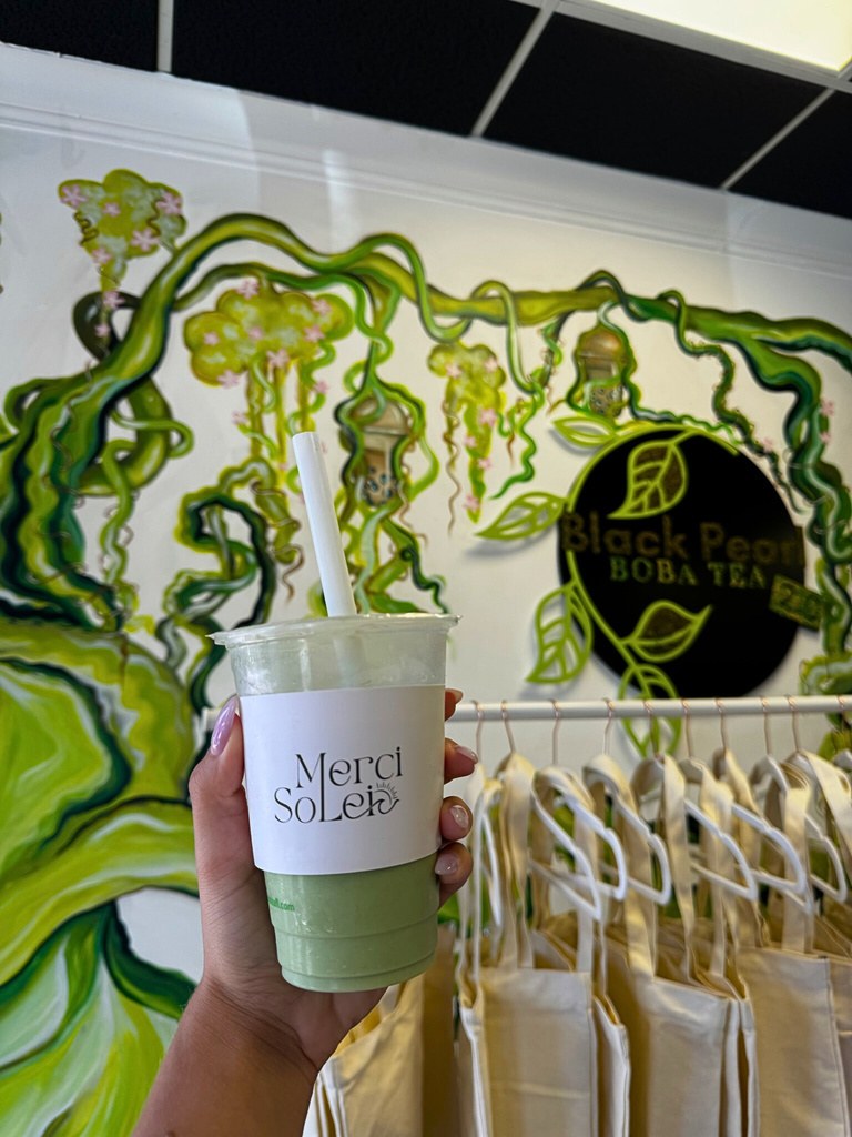 Merci Solei branded drink in front of Black Pearl signage